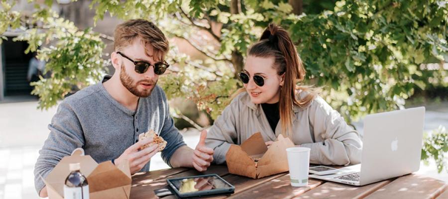 Couple in the sun with food and laptop