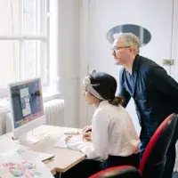 Design student working with one of the class teachers on a Mac