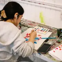 Student sitting down painting on our Design course