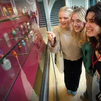 Three students pointing to artefacts at the National Museum of Scotland
