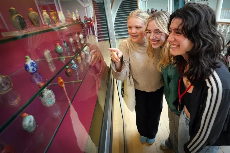 Three students pointing to artefacts at the National Museum of Scotland