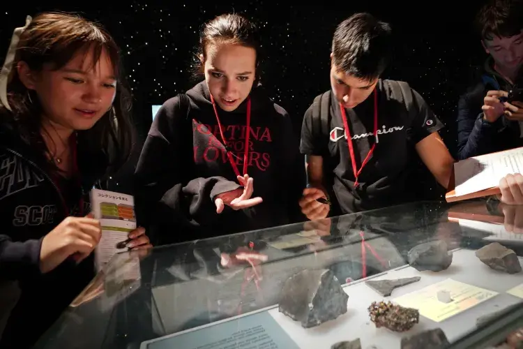 Three students pointing to artefacts at the National Museum of Scotland