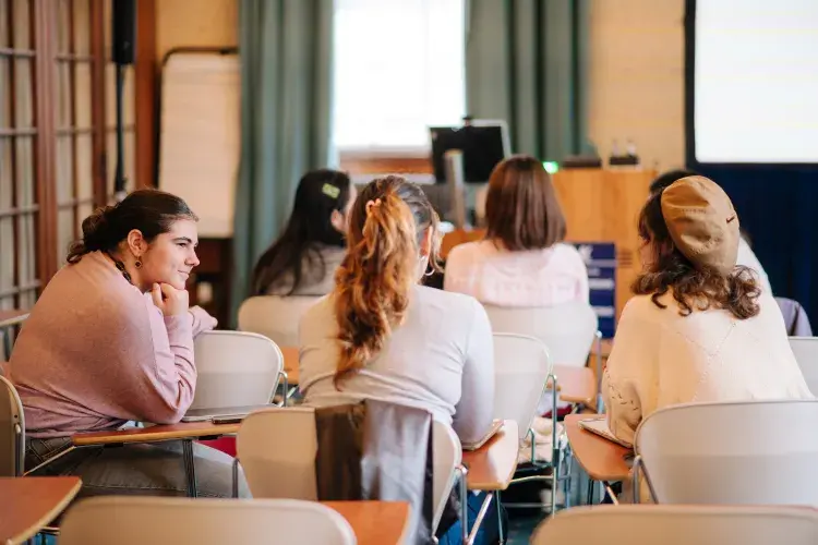 Image showing the backs of students facing the front of a classroom 